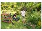 Couple dans un jardin avec tondeuse, coupe-bordure et table de jardin avec outils.