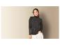Une femme porte un pull à col roulé gris foncé et un pantalon blanc.