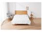 Une couette blanche sur un lit en bois dans une chambre claire.
