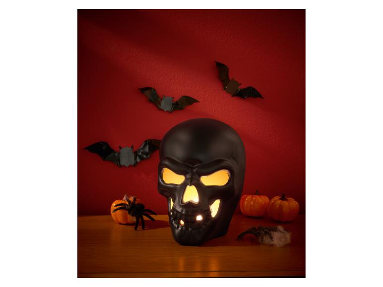 Crâne noir illuminé avec chauves-souris décoratives, citrouilles et araignées.