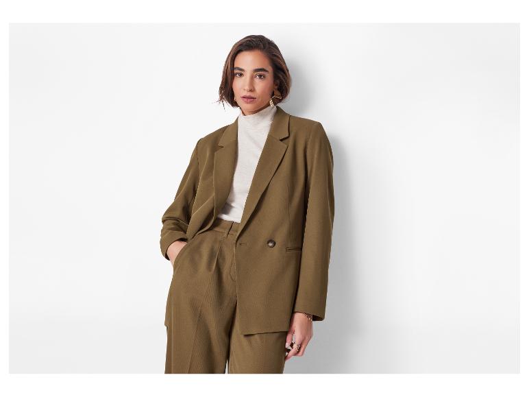 Femme en costume marron olive, blazer et pantalon, portant un col roulé crème.