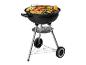 Un barbecue noir sur roues, sur lequel sont grillés des saucisses, du poulet et des légumes.