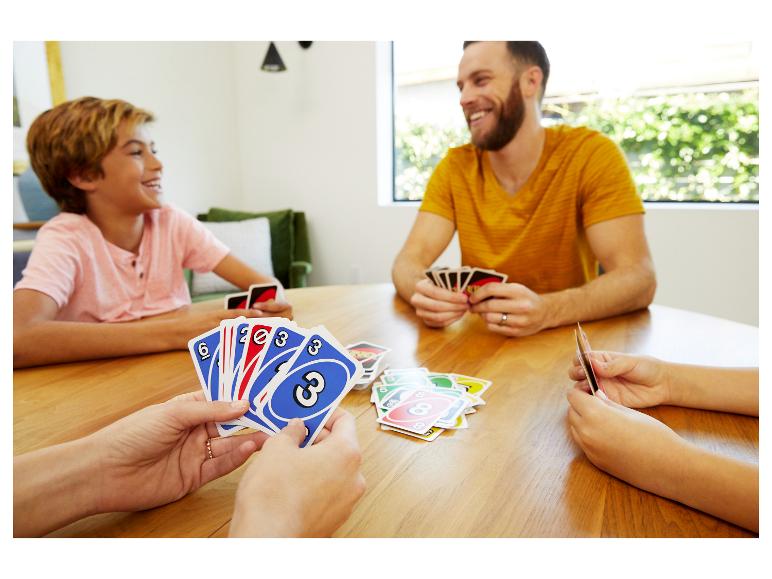 Famille jouant au jeu de cartes UNO autour d'une table en bois.