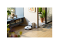 Aspirateur robot blanc sur un sol en bois, près de sa station de charge dans un salon moderne.