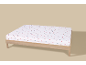 Drap-housse blanc à motifs de Noël colorés sur un cadre de lit en bois.
