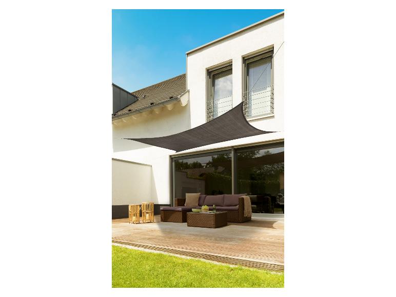 Une voile d'ombrage noire au-dessus d'une terrasse avec un salon de jardin marron.