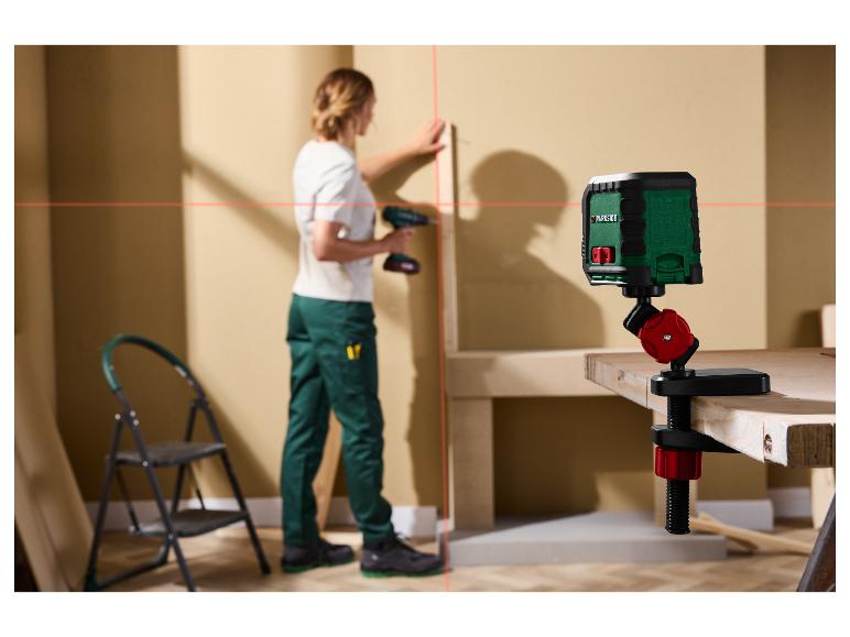 Un niveau laser Parkside projette des lignes rouges sur un mur pendant qu'une personne travaille.