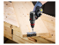 Un ouvrier utilise une perceuse Parkside pour visser une charnière sur une surface en bois.