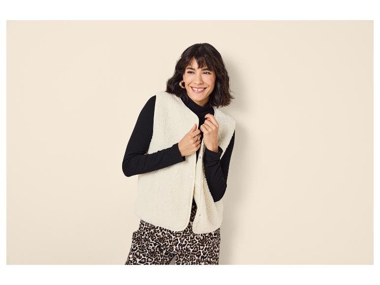 Femme en col roulé noir, gilet en sherpa et pantalon imprimé léopard.
