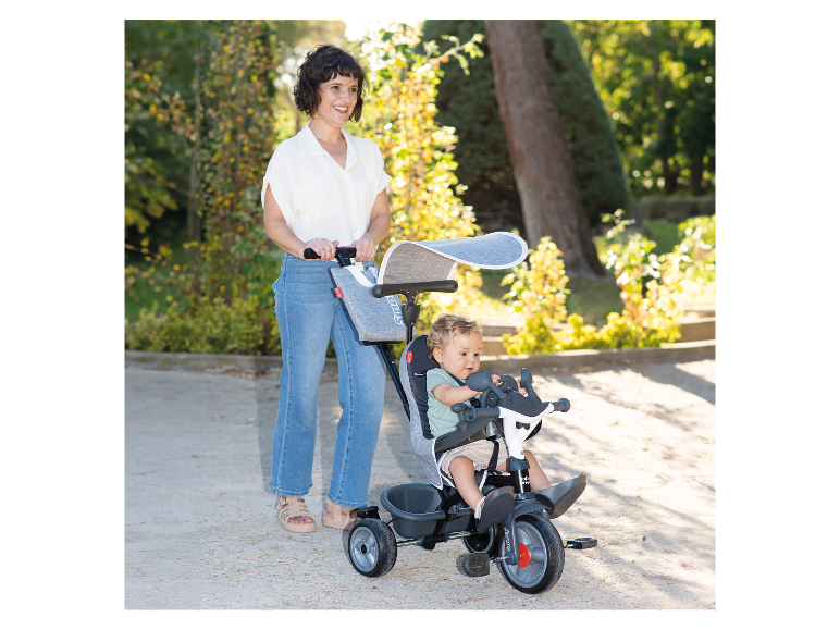 Tricycle Smoby Baby Drive et enfant dans un parc.