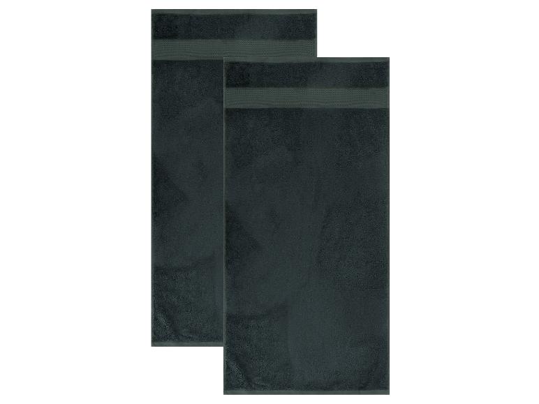 Deux serviettes de bain gris foncé avec des bandes décoratives, pliées et superposées.