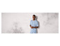 Homme portant un t-shirt et un short bleu clair devant un mur blanc.