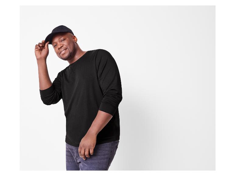 Homme souriant en t-shirt noir à manches longues et casquette noire.