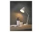 Une lampe de bureau blanche, un carnet et des stylos sur un bureau en bois.