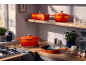 Batterie de cuisine en fonte orange sur un plan de travail et une étagère en bois