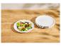 Salade fraîche dans une assiette blanche avec une pile d'assiettes à côté sur une table en bois.