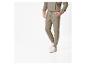 Un homme porte un pantalon de survêtement vert et des baskets blanches.
