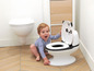 Un bébé assis à côté d'un pot de panda dans une salle de bain.