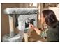 Femme nourrissant un chat dans un arbre à chat gris avec poteaux à griffer.