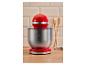 Robot pâtissier rouge avec un bol en acier inoxydable sur un comptoir en bois.