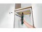 Une perceuse sans fil perçant une étagère en bois à l'intérieur d'une armoire.