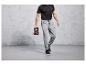 Homme en survêtement gris et baskets noires, tenant un kettlebell.
