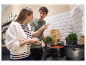 Un couple cuisine dans une cuisine moderne, utilisant des casseroles et des ustensiles de cuisine élégants.