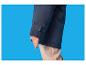 Un enfant en veste bleu foncé et pantalon beige sur fond bleu.
