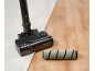 Tête d'aspirateur sur un tapis et un parquet, avec un rouleau brosse à côté.