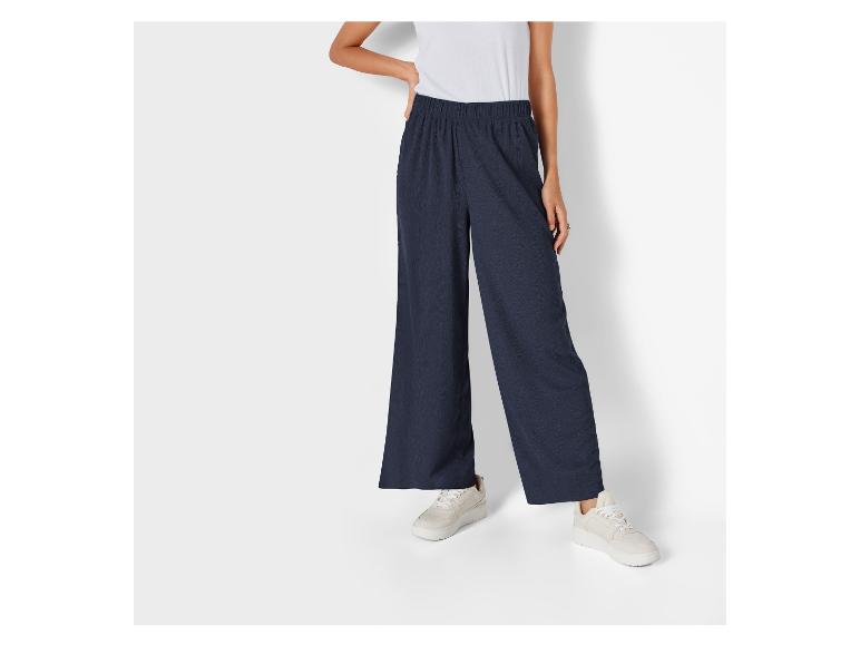 Pantalon large bleu marine et baskets blanches.