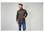 Un homme portant une veste matelassée vert foncé avec des manches en tricot et un jean bleu.