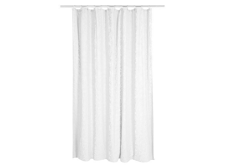 Rideau de douche blanc gaufré sur une tringle argentée avec anneaux.