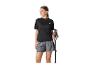 Femme en t-shirt noir et short gris, tenant des bâtons de randonnée.
