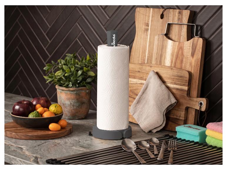 Porte-serviettes en papier gris avec des fruits, des planches à découper et des ustensiles de cuisine.