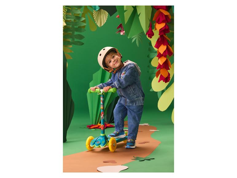Enfant avec casque et trottinette dans un décor de jungle en papier.