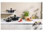 Casseroles noires avec couvercles en verre, tomates fraîches, basilic et accessoires de cuisine.