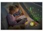 Deux enfants lisent un livre dans une tente avec une veilleuse tortue projetant des étoiles.