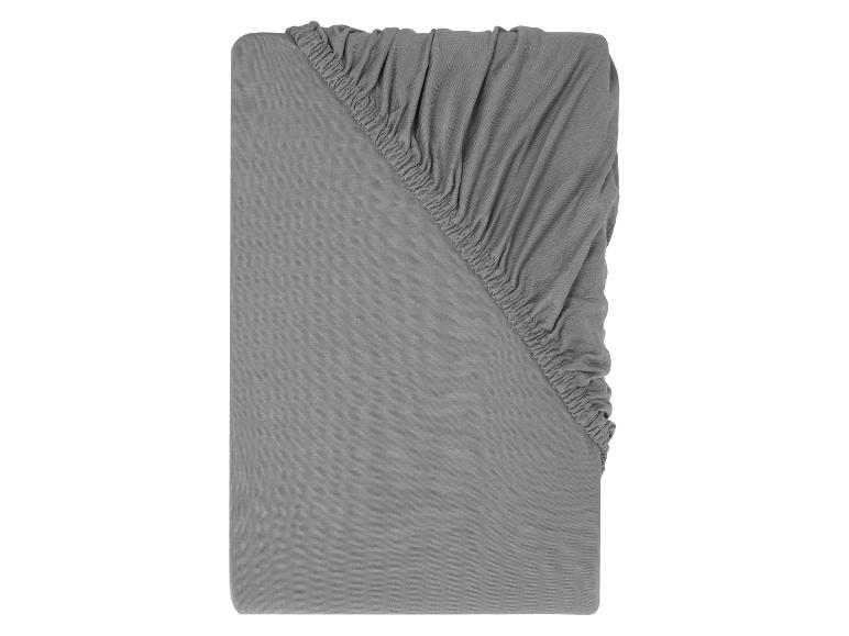 Drap-housse gris avec coins élastiques.
