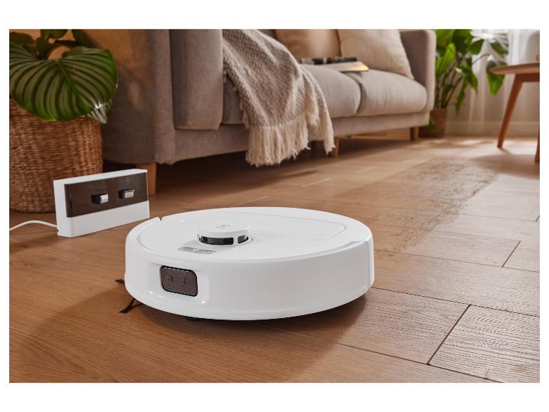 Un robot aspirateur sur un sol en bois dans un salon.