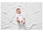 Un bébé allongé sur une couverture blanche, portant un body blanc avec l'inscription 'SMILE everyday'.
