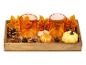 Plateau en bois avec bougeoirs orange, décorations d'automne et petites citrouilles.