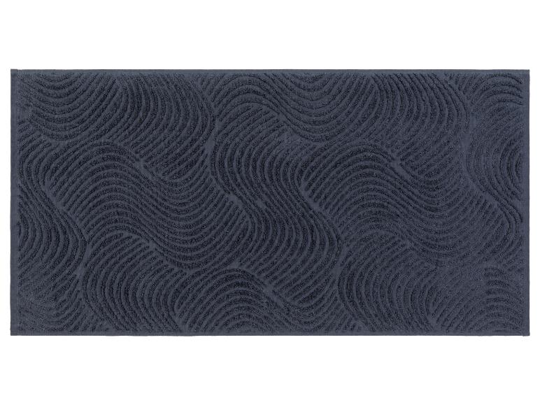 Un tapis de bain bleu foncé avec un motif ondulé.