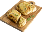 Focaccia au pesto et fromage sur une planche en bois, coupée en morceaux.