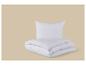 Couette et oreiller blancs pliés sur fond beige.