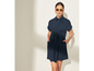Une femme porte une robe bleu foncé avec un nœud et des lunettes de soleil.