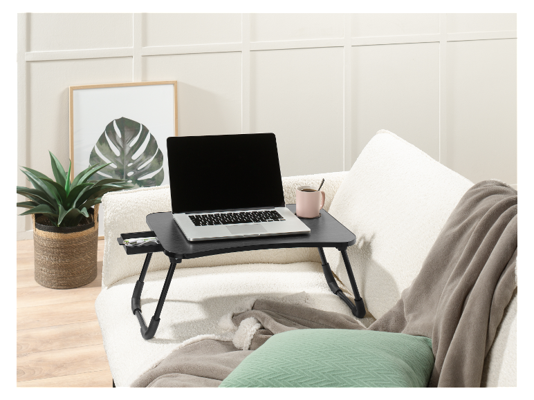 Un ordinateur portable sur une table pliable sur un canapé.