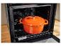 Une cocotte orange en fonte sur la grille d'un four Silvercrest.