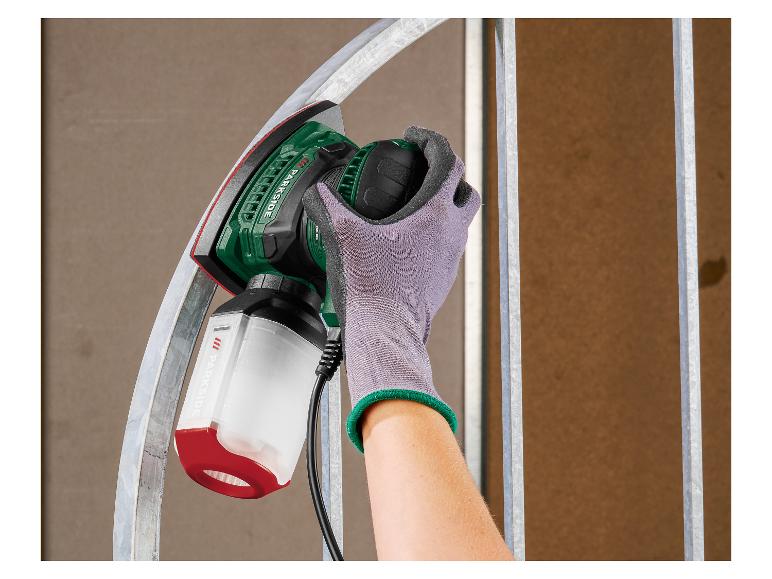 Ponceuse à main avec bac à poussière ponçant une surface métallique.