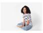 Une femme porte un t-shirt à rayures et un jean avec des baskets blanches.