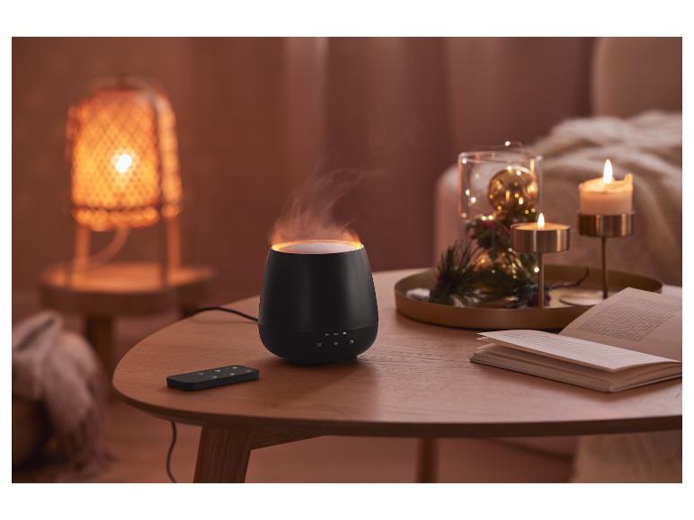 Un diffuseur d'arômes noir avec une télécommande sur une table en bois.